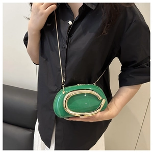 Detail of green patent leather mini pillow bag with gold C-handle and chain strap