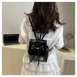 Detail of black synthetic leather drawstring backpack with cute white cat face and paw prints