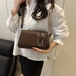 Brown rectangular crossbody flap bag with silver chains and buckles on white shirt