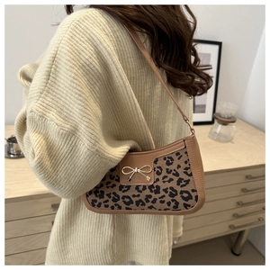 Détail du sac léopard avec un fermoir nœud doré et une fine bandoulière en cuir
