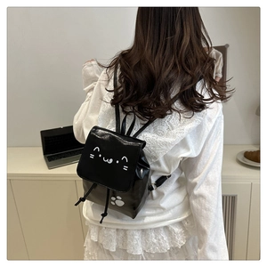 Detail of a mini black PU leather backpack featuring a white cat face and paw print design