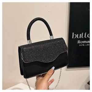 Detail of elegant black crossbody bag with sequined flap and delicate metal chain strap