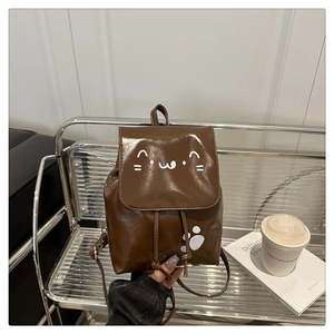 Detail of a brown small backpack featuring a cute cat face design and shiny PU leather finish