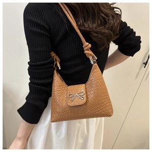Détail du sac à bandoulière en cuir tressé camel avec nœud argenté et bandoulière nouée