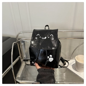 Close-up of black leather mini backpack featuring cute white cat face and paw prints