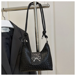 Détail d'un sac demi-lune tressé noir avec nœud argenté et bandoulière à nœuds