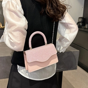 Pink sequin crossbody bag with silver chain strap shown in a stylish interior setting