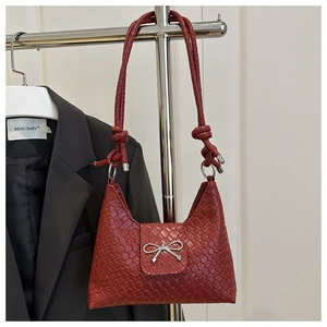 Détail du sac bandoulière tressé bordeaux avec nœud argenté et bandoulière nouée