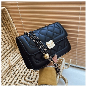 Detail of black quilted leather crossbody bag with gold square lock and metal chain strap