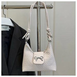 Détail du sac demi-lune tressé crème avec fermoir nœud argenté et bandoulière nouée