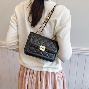 Quilted black square shoulder bag with gold clasp shown on model in a summer setting