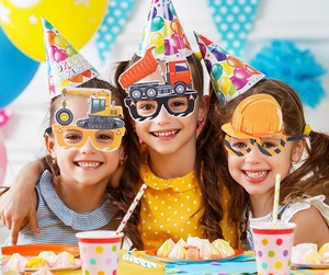 Trois enfants portant des lunettes de fête thème chantier avec excavatrice et casque jaune