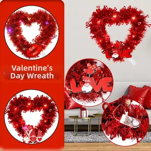 Detail of red tinsel heart wreath with LED lights and festive Kiss Me ornaments