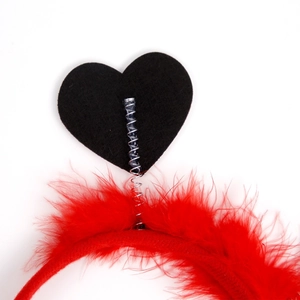 Détail du serre-tête rouge duveteux avec un cœur noir monté sur un ressort métallique