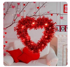 Close-up of heart-shaped red tinsel wreath featuring warm white LED fairy lights
