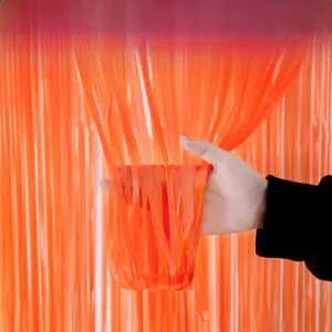 Close-up of bright orange tinsel curtain fringe with reflective metallic finish