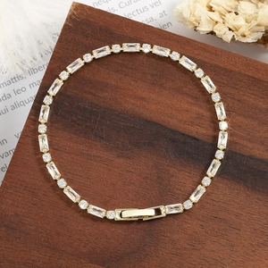 Elegant gold-plated tennis bracelet with baguette and round CZ stones on a wooden base.