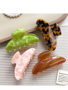 Detail of four acetate hair claws in marble and floral patterns on elegant white background