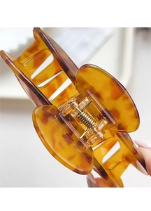 Detail of tortoise shell acetate hair claw clip showing amber texture and gold spring
