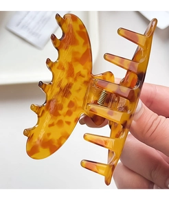 Macro view of a large butterfly claw clip featuring glossy amber tortoiseshell patterns