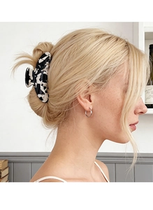 Close-up of a large black and white marble acetate hair claw clip on model's bun