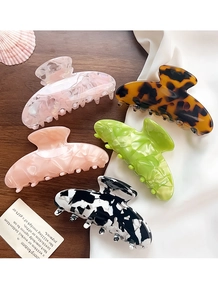 Detailed view of five colorful acetate claw clips on silk fabric and wooden background