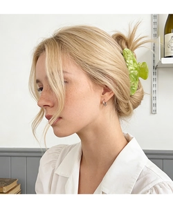 Detailed side view of a large light green marbled acetate hair claw clip on blonde hair