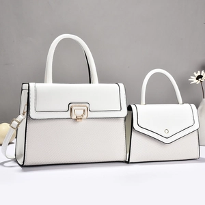 Detail der weißen Handtasche mit gewebten Texturen und goldenen Metallbeschlägen im Set