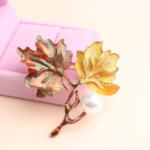 Elegant maple leaf brooch featuring colorful enamel glitter finish and a pearl accent