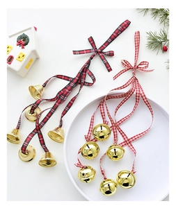 Close-up of festive golden metal bells with plaid bows for Christmas tree decoration