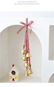 Close-up of golden Christmas metal bells with red and white gingham ribbon bow for decor