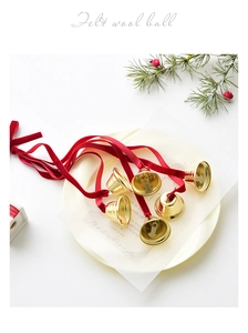 Close-up of golden metal Christmas bells with red velvet ribbons for tree decoration