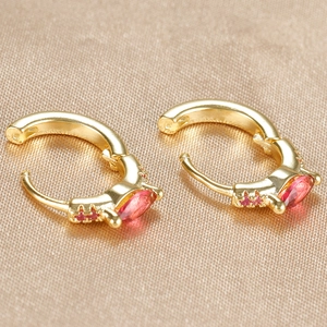 Macro shot of gold-plated hoop earrings with inlaid marquise-cut red zircon stones
