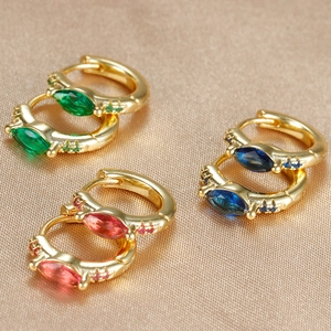 Macro detail of gold hoop earrings with marquise-cut emerald, sapphire, and rose stones