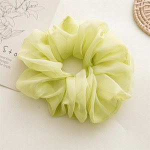 Macro detail of a large pastel green chiffon scrunchie with soft pleated texture