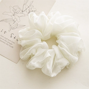 Detailed view of fluffy cream chiffon scrunchie with layered pleats on aesthetic card