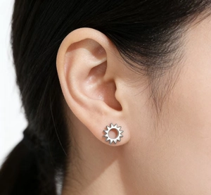 Close-up of a 925 sterling silver sunflower stud earring worn on a model's ear lobe