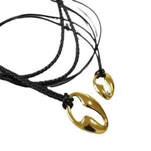 Modern gold hollowed-out organic pendant necklace with black braided cord on white background
