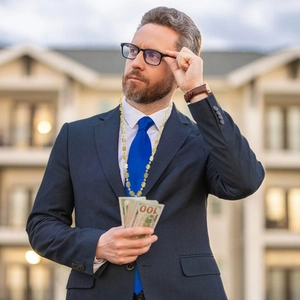 Détail d'un collier pendentif signe dollar doré porté par un homme en costume