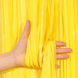 Close-up of vibrant yellow macaron fringe curtain for birthday party wall decoration