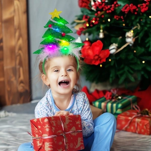 Detail of child wearing a glowing green Christmas tree headband with LED stars