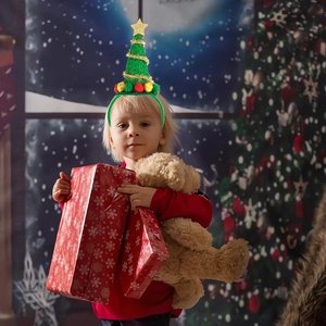 Close-up of a green Christmas tree headband with golden star and colorful pom-poms