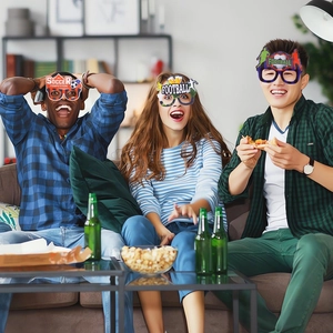 Three people wearing soccer party glasses during a lively sports event at home
