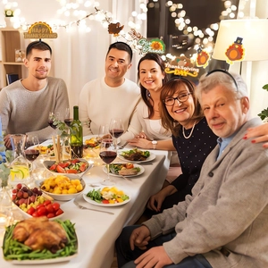 Familie trägt Thanksgiving-Stirnbänder mit Truthahnmotiven und Grüßen am Esstisch