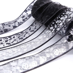 Detail of black Halloween sheer ribbon with silver skull and spider web foil print