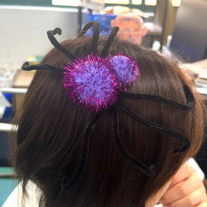 Détail d'une pince à cheveux araignée violette pour Halloween sur cheveux brun foncé