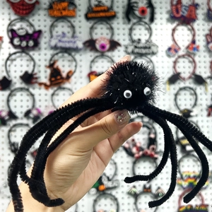 Gros plan d'une pince à cheveux araignée noire en peluche avec des yeux mobiles pour Halloween
