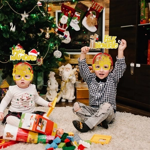 Toddlers wearing Feliz Navidad headbands and festive glasses in a Christmas setting