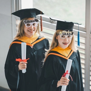 Close-up of graduates wearing glittery GRAD and Congrats glasses at a graduation party