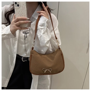 Coffee brown underarm bag featuring textured fabric and a gold bow detail in a mirror selfie